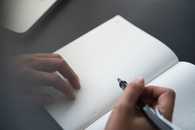 Close-up of hand holding pen over book