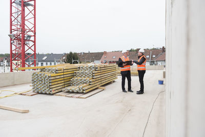 Two men wearing safety vests talking on construction site