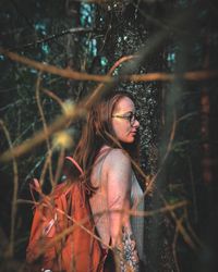 Woman standing by tree trunks in forest