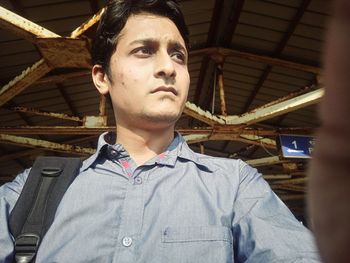 Low angle view of young man looking away at railroad station