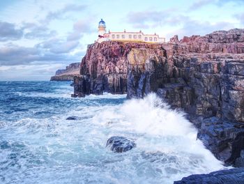 Famous view to neist point lighthouse on end of world. foamy evening blue sea strikes against cliff