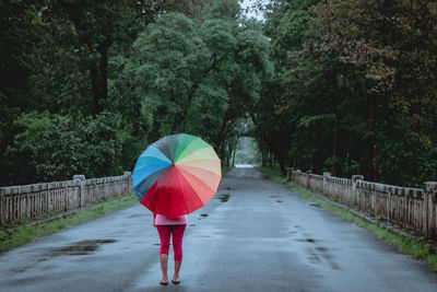 Rear view of woman standing on wet road