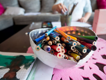 Midsection of girl with multi colored pencils on table