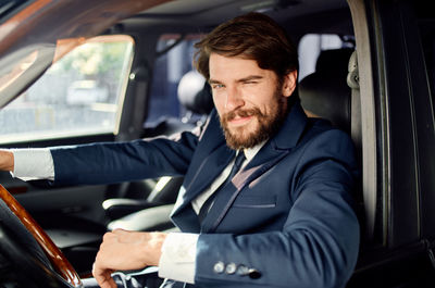 Portrait of businessman winking while sitting in car