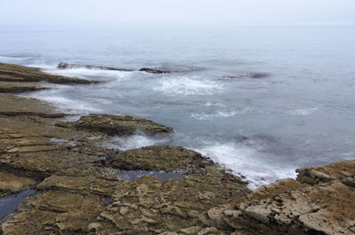 Scenic view of rocks on beach against sky