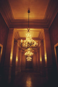 Low angle view of illuminated chandelier hanging in corridor