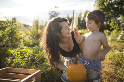 Shirtless son playing with mother at community garden