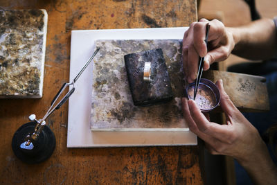 Cropped image of craftsperson working on jewelry at bench in workshop
