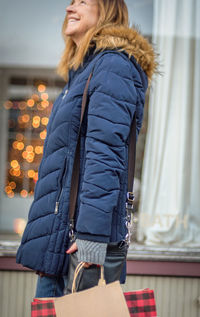 Smiling woman with shopping bags standing in city