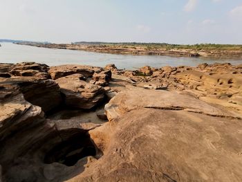 Rocks on shore by sea against sky