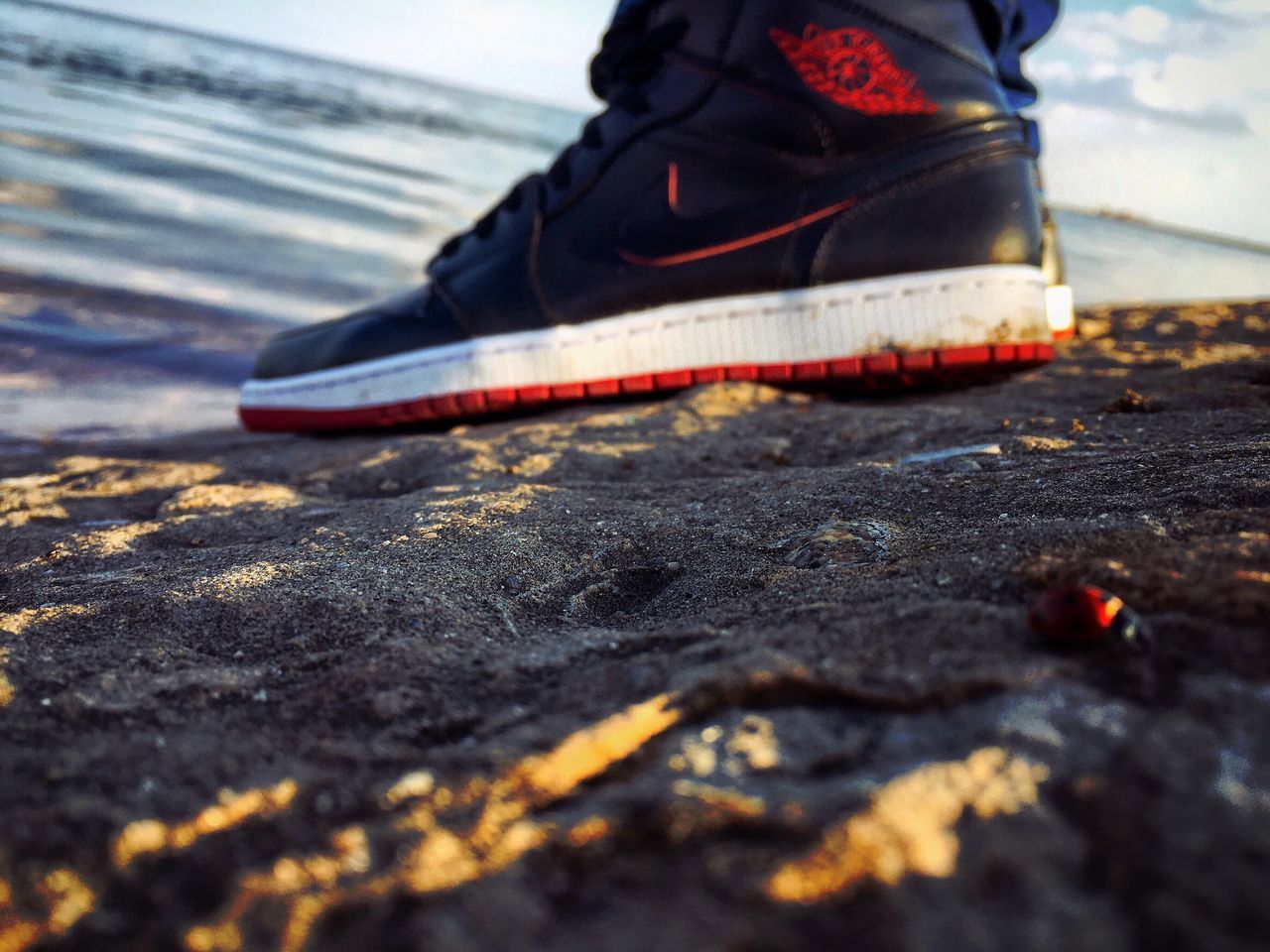selective focus, street, surface level, close-up, transportation, focus on foreground, shoe, road, asphalt, outdoors, low section, beach, day, mode of transport, car, sand, sunlight, person