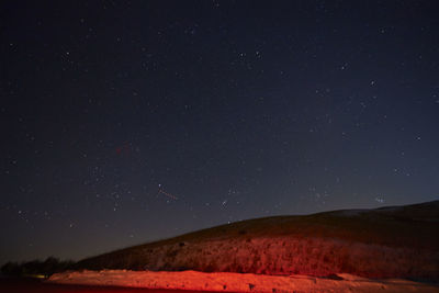Low angle view of hill against star field sky during night