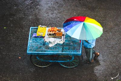 Low section of person holding umbrella on wet street