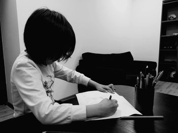 Girl writing on page at home