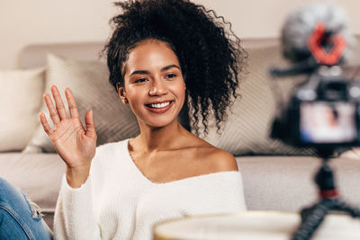 Portrait of smiling young woman sitting on sofa at home