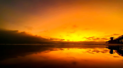 Scenic view of sea against dramatic sky during sunset