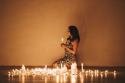 Woman sitting by illuminated lighting equipment