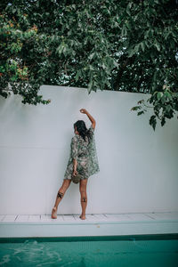 Rear view of woman standing by swimming pool