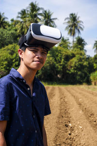 Portrait of man wearing virtual reality simulator while standing on field against sky