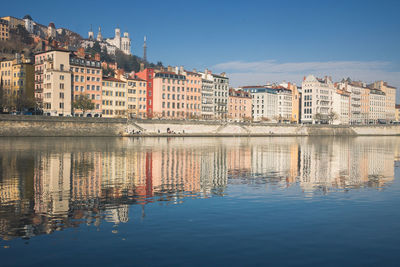 Reflection of buildings in lake against blue sky