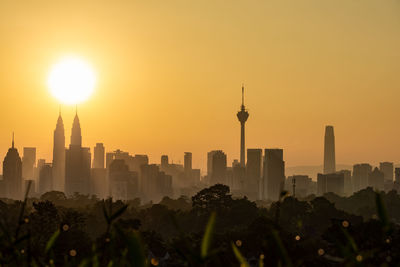 Modern buildings in city against sky during sunset