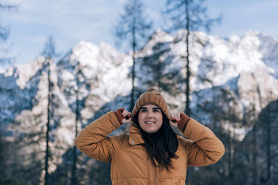 Portrait of young woman standing against trees