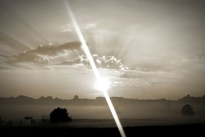 Sun shining through clouds over sea