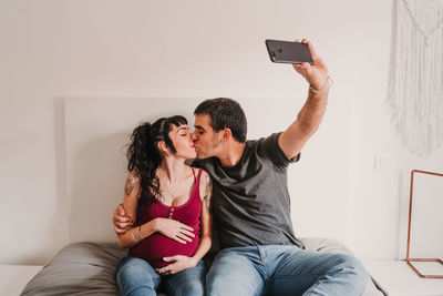 Man photographing woman using mobile phone
