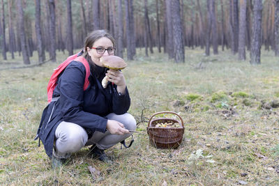 Portrait of smiling mature woman holding edible mushroom in forest