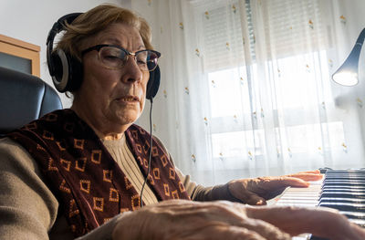 Caucasian elderly woman learning music and playing the musical keyboard.