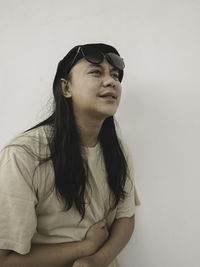 Young woman looking away against blue background