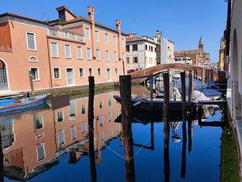 Sailboats moored in canal by buildings against sky in city