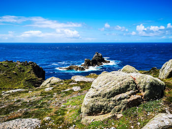 Rocks by sea against blue sky