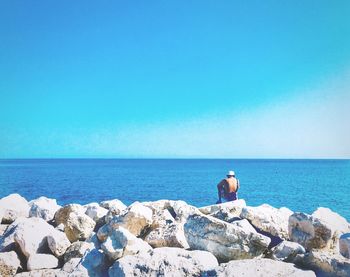 Woman looking at sea against clear blue sky