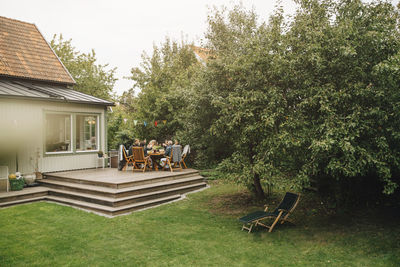 Senior male and female friends enjoying dinner while sitting dining table during garden party