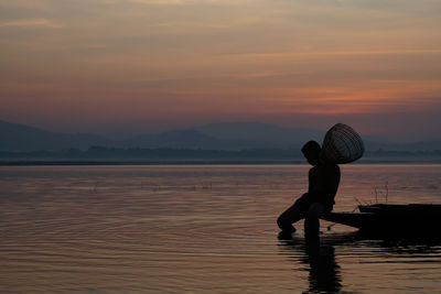 Silhouette man on beach against sky during sunset