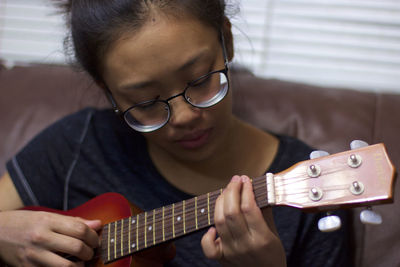 Teenage girl playing ukulele at home