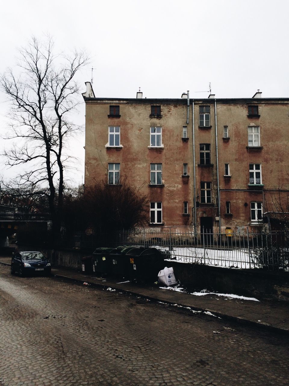 architecture, building exterior, built structure, window, building, clear sky, transportation, residential building, street, city, car, residential structure, bare tree, land vehicle, tree, day, house, mode of transport, road, outdoors