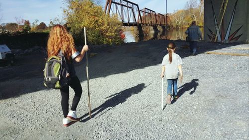 Rear view of siblings walking on road