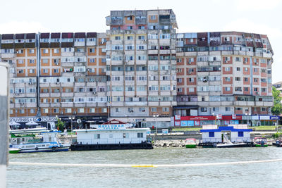 Buildings by river against sky in city