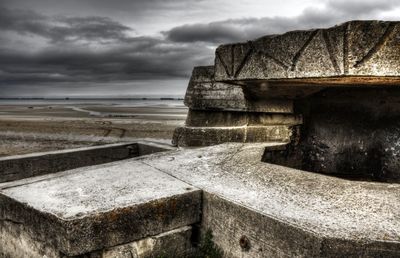 Stone wall by sea against sky