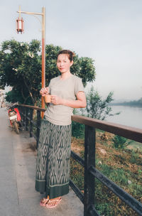 Portrait of mature man standing by railing against sky