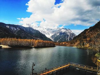 Scenic view of lake by snowcapped mountains against sky