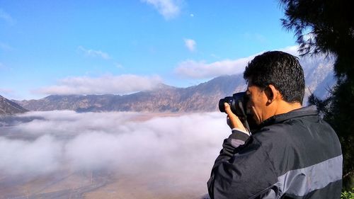  man photographing foggy landscape against mountain