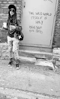 Full length portrait of man wearing sunglasses standing against wall