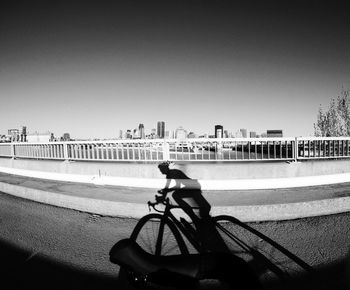 Man riding bicycle on city against clear sky