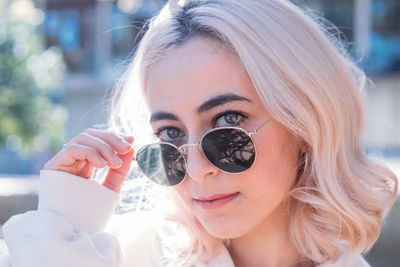 Portrait of young woman holding sunglasses