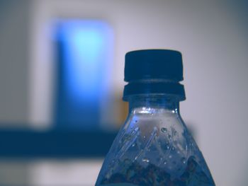 Close-up of illuminated bottle on table against wall
