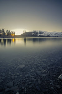 Scenic view of frozen lake against sky during sunset