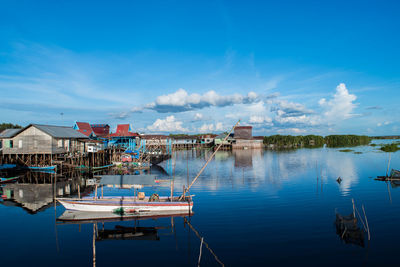 Boats moored in calm lake against blue sky